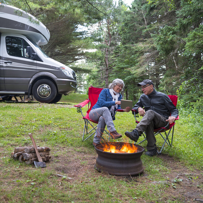 Couple looking at digital tablet near campfire.